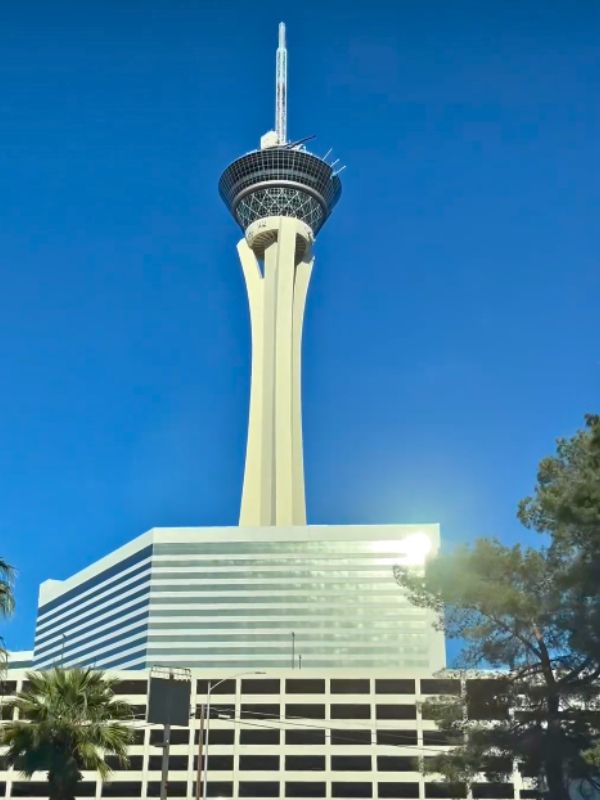 Stratosphere hotel Stratosphere v Las Vegas, vysoká věž s vyhlídkovou částí a atrakcemi na vrcholu, moderní fasáda hotelu, okolní město a poušť v dálce, slunečný den, panoramatický pohled na Las Vegas Strip a okolí, rušná turistická atmosféra
