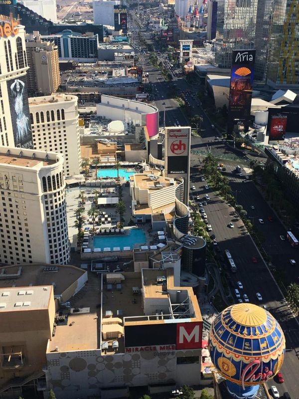 Street Vegas letecký pohled na Las Vegas Strip, hlavní ulice lemovaná hotely a kasiny po stranách, světla budov a neonové nápisy, auta a ruch města, večerní nebo noční atmosféra, poušť v pozadí