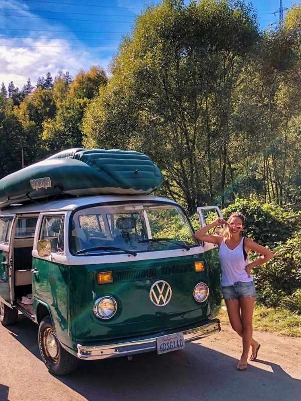 Žena stojí vedle starého VW autobusu, připravena vyrazit sjíždět vodu v Českém Krumlově.