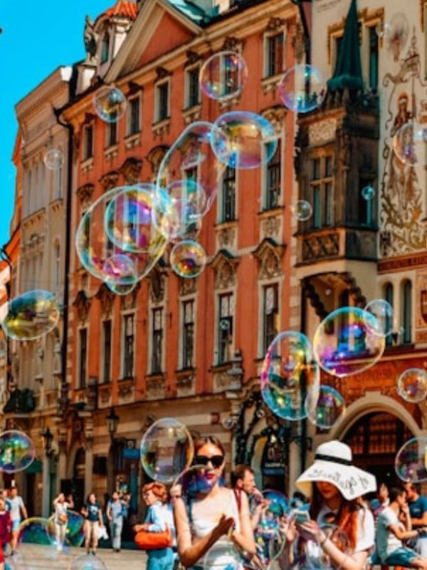 Lidé, obří bubliny a historické budovy vytvářející letní atmosféru