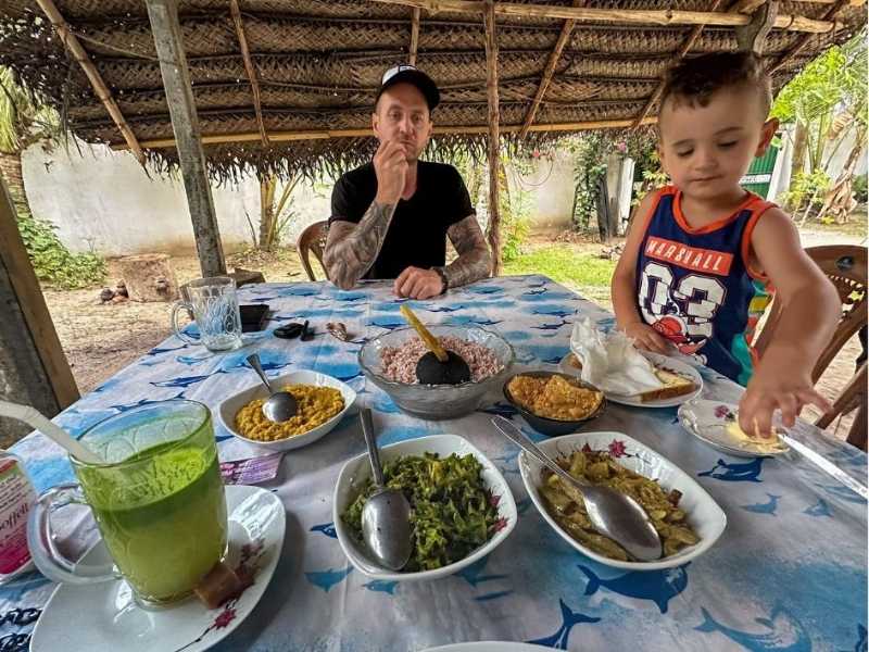 muž a dítě sedí u stolu plného jídla rozděleného do misek, typická srílanská kuchyně