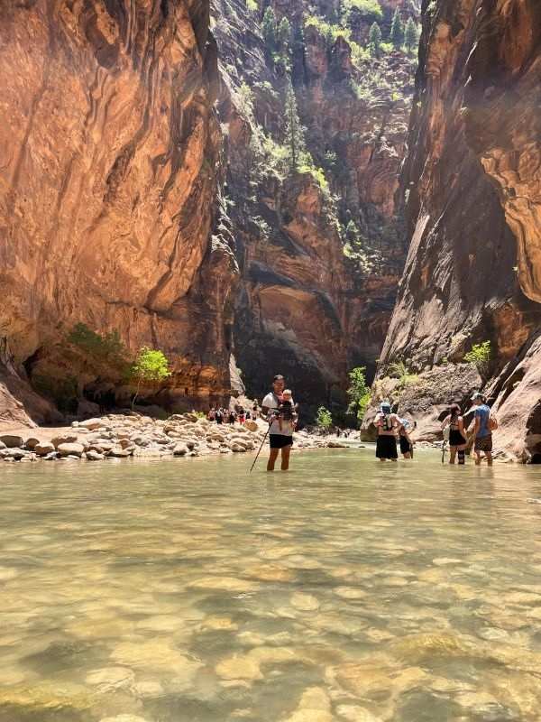 Hiking Narrows muž a dítě pózují pro fotku v kaňonu The Narrows v národním parku Zion v Utahu, čistá voda plná kamenů a vysoké skály kolem