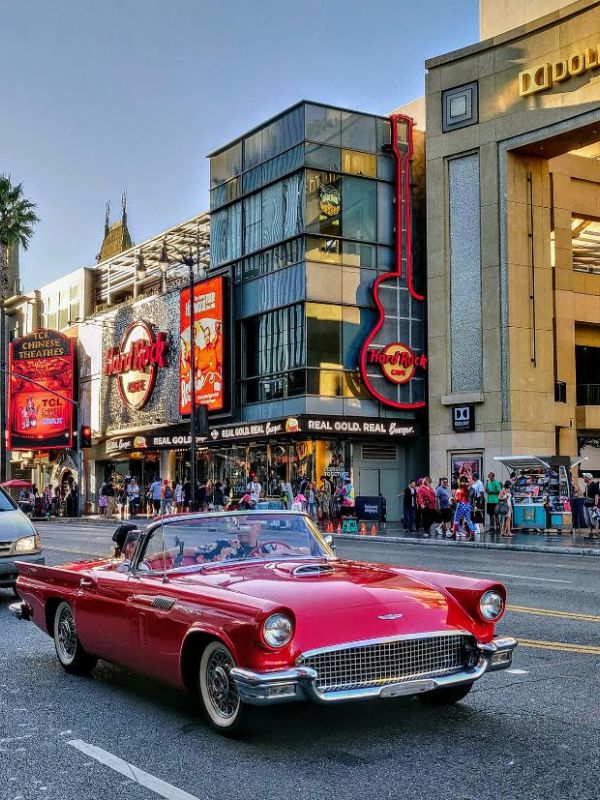 červené sportovní retro auto jede po Hollywood Blvd, v pozadí obchody a Hard Rock Cafe