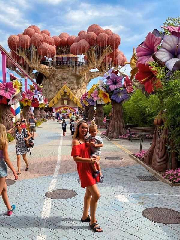 **Gardaland, balónky a žena držící malého chlapce, atmosféra je živá a hravá.**