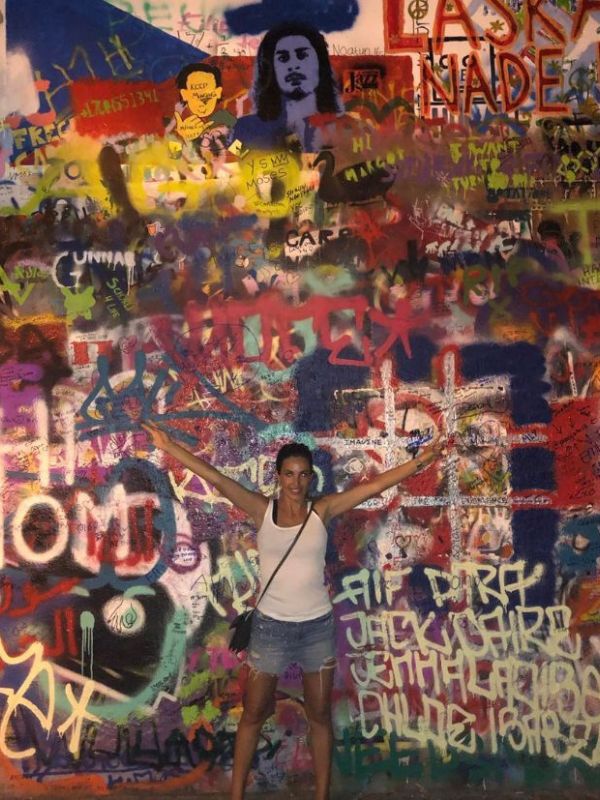 Žena pózuje před Lennonovou zdí v Praze