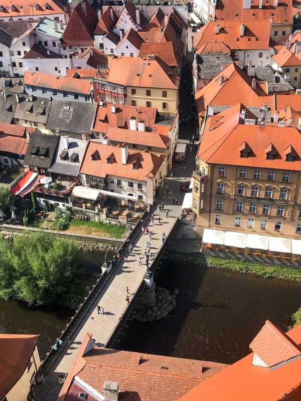 Letecký pohled na červené střechy Českého Krumlova s řekou a zelení kolem