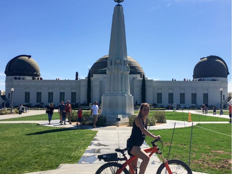 Griffith Observatory v pozadí a žena na kole v popředí