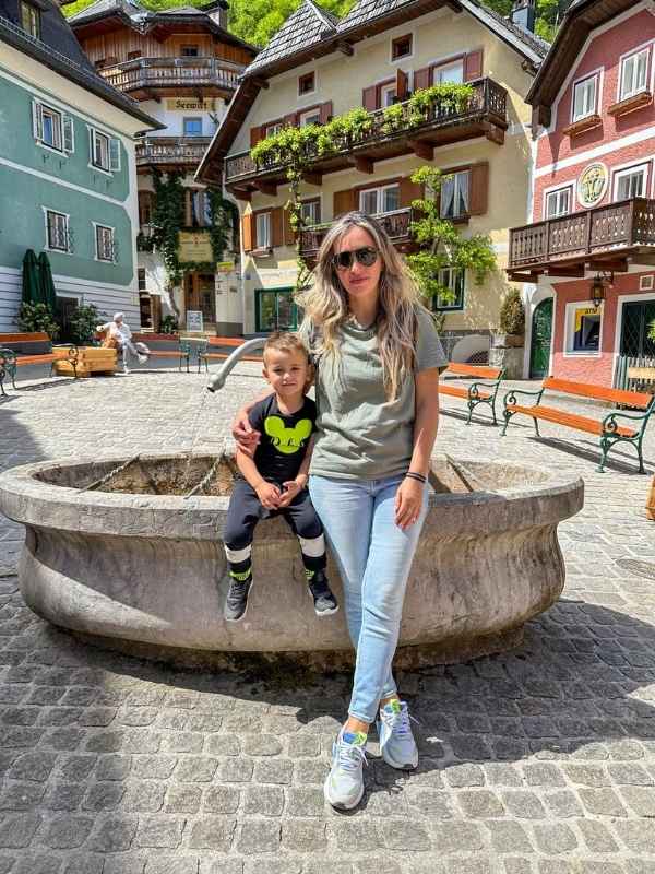 Fontána na náměstí v Hallstattu, na ní sedí matka s dítětem