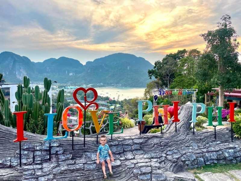 Chlapec sedí přes barevný nápis I Love Phi Phi