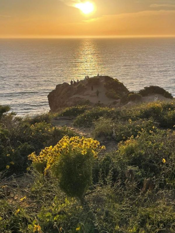 Point Dume skála s lidmi na vrcholu sledujícími západ slunce