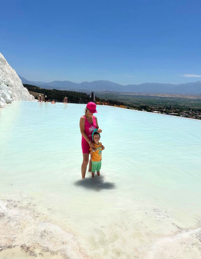 Pool žena a chlapec stojí v bílo-modré vodě v tureckém Pamukkale