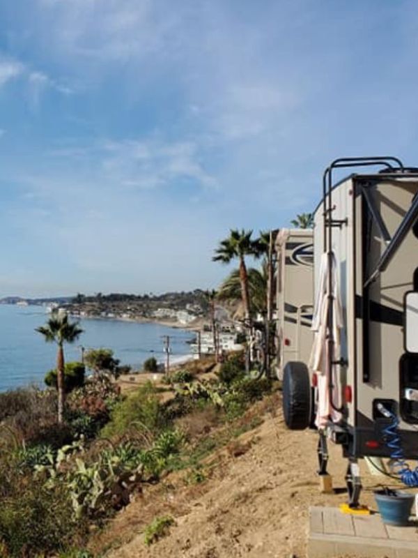 obytná auta zaparkovaná na okraji útesu s výhledem na zelené kopce a oceán