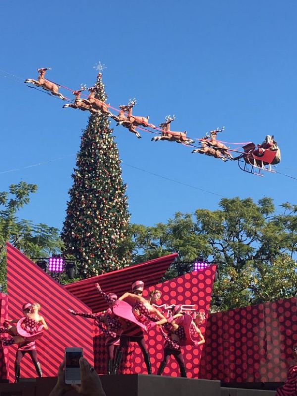 taneční vystoupení s vánočním stromečkem v pozadí a Santou v saních tažených deseti soby přes oblohu