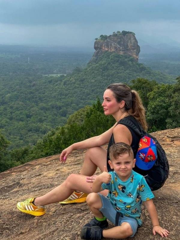 žena a malé dítě odpočívají na vrcholku Pidurangala Rocku, za nimi je Sigiriya Rock