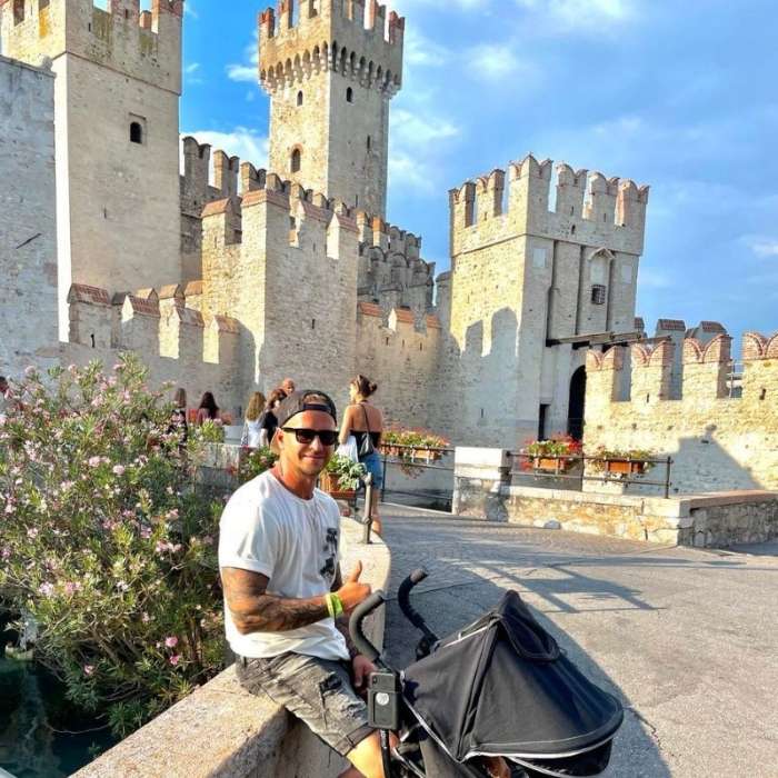 **Hrad v Sirmione s modrou oblohou, otec s kočárkem.