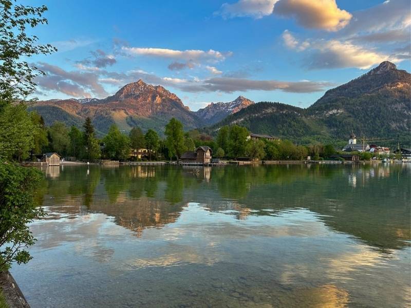 Odraz hor a zapadu slunce na hladině vody v Rakousku