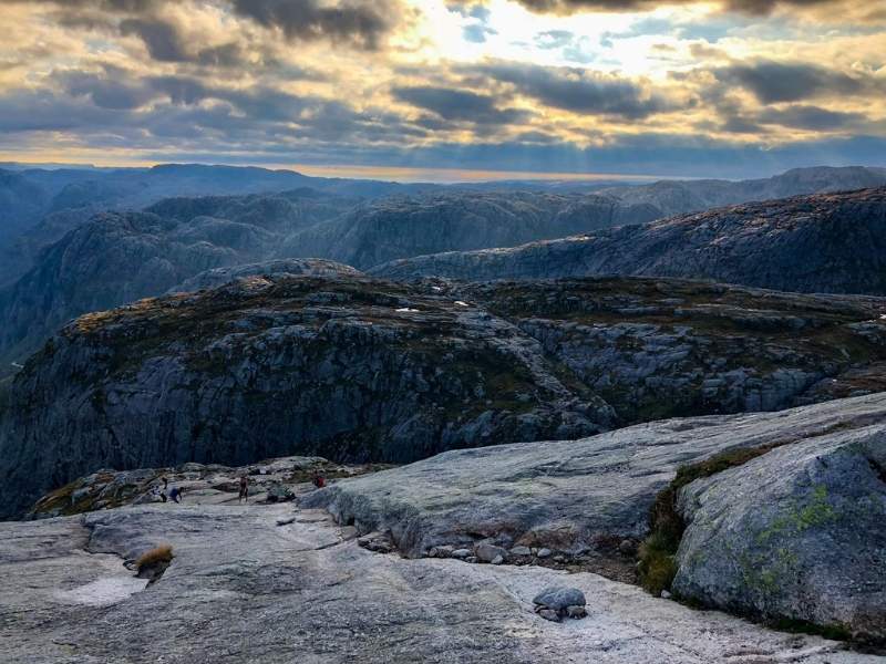 Sluneční paprsky procházejí zamračenou oblohou nad skalami