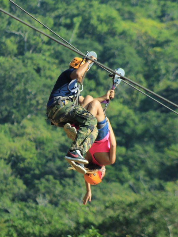 Muž přidržuje ženu na ziplině, která visí hlavou dolů.