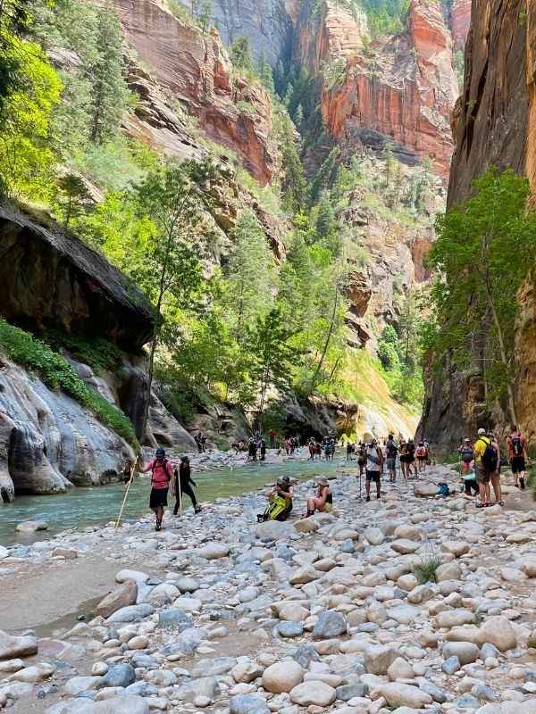 Trailhead začátek stezky The Narrows v národním parku Zion, lidé stojí u břehu i ve vodě, kolem vysoké skály