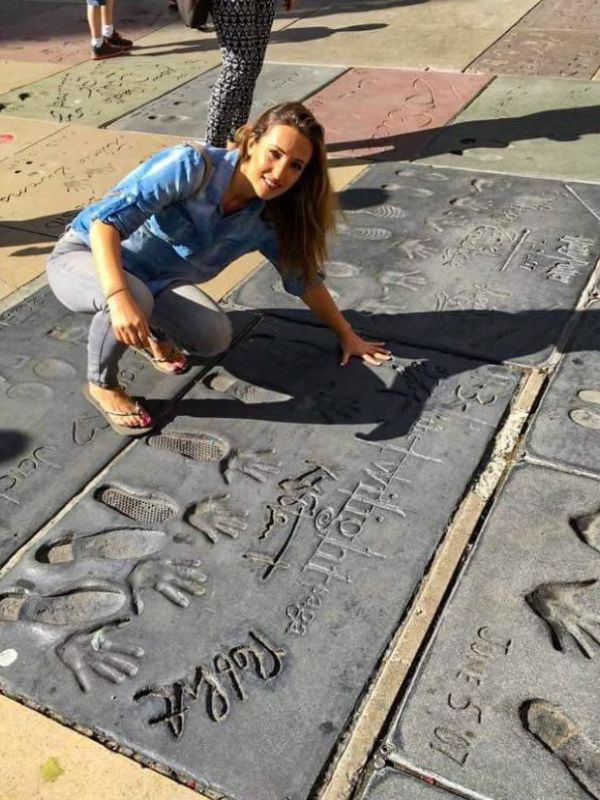 žena v džínové košili pokládá ruku na otisk ruky v cementu, otisky jsou z Twilight na Chodníku slávy