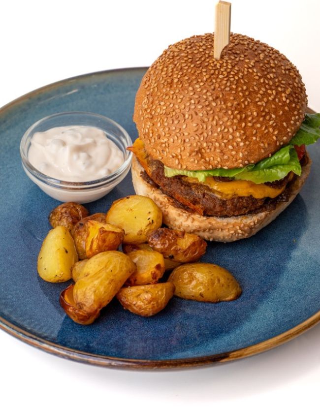 Burger s pečenými bramborami pěkně naservírovaný na talíři