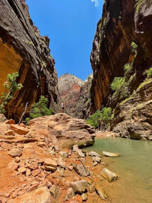 Zion NP řeka obklopená červenými kameny a muž pózující pro fotku v národním parku Zion
