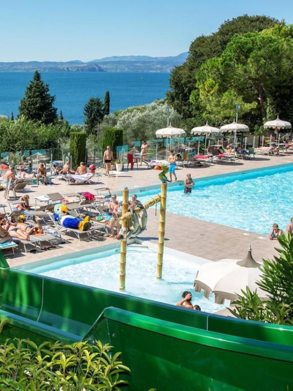 **Bazén s lidmi a výhledem na jezero Garda.**