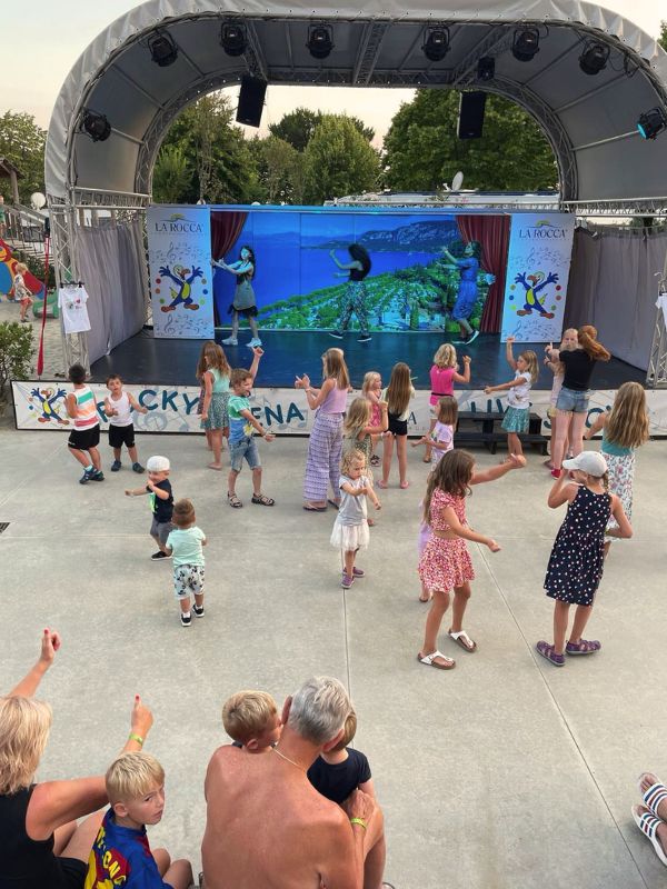 **Dětské aktivity v kempu, děti tančí před jevištěm.**