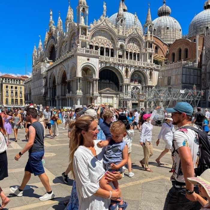 žena drží malého chlapce v turistickém davu na náměstí svatého Marka v Benátkách