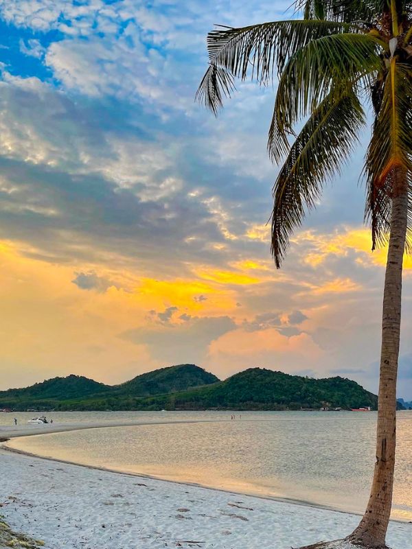 Pláž, oceán, palmy a západ slunce v Thajsku.