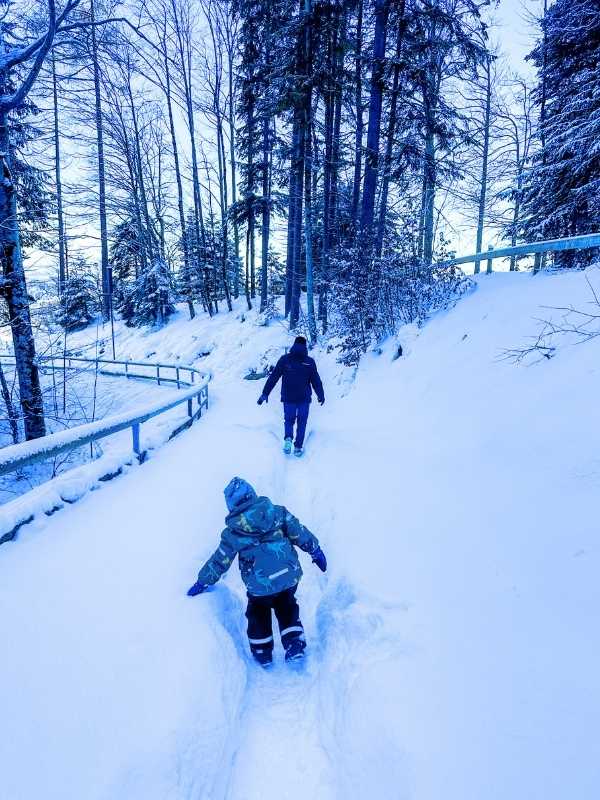 Muž a chlapec se brodí vysokým sněhem.