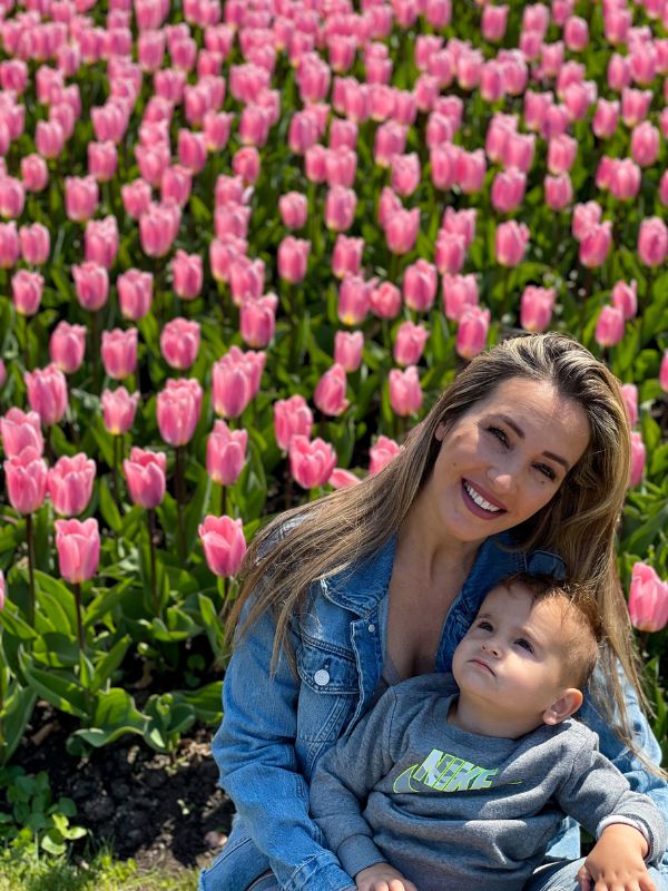 Žena se synem před záhonem růžových tulipánů.