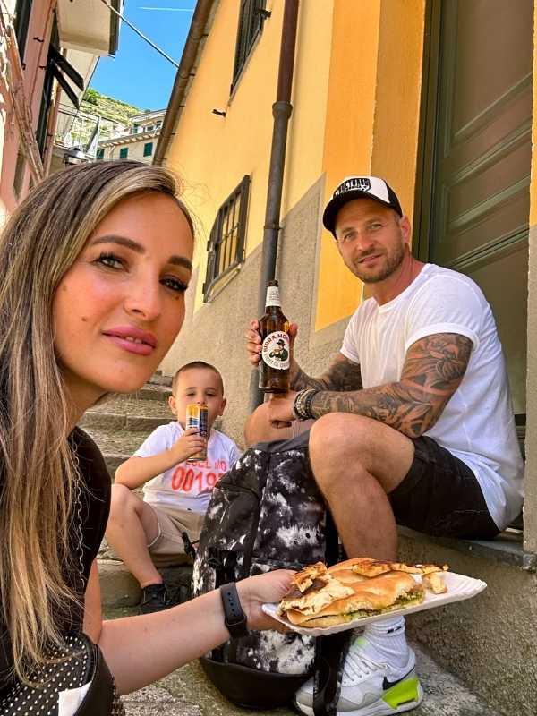 rodina si užívá italské pochoutky a pivo na schodech v Corniglia