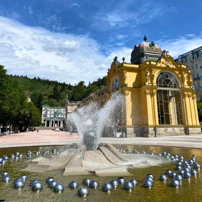 Kolonáda a fontána v Mariánských Lázních pod modrou oblohou.