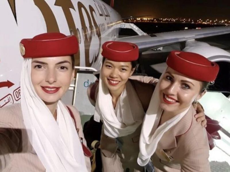 Tři letušky Emirates se usmívají v červených kloboučcích