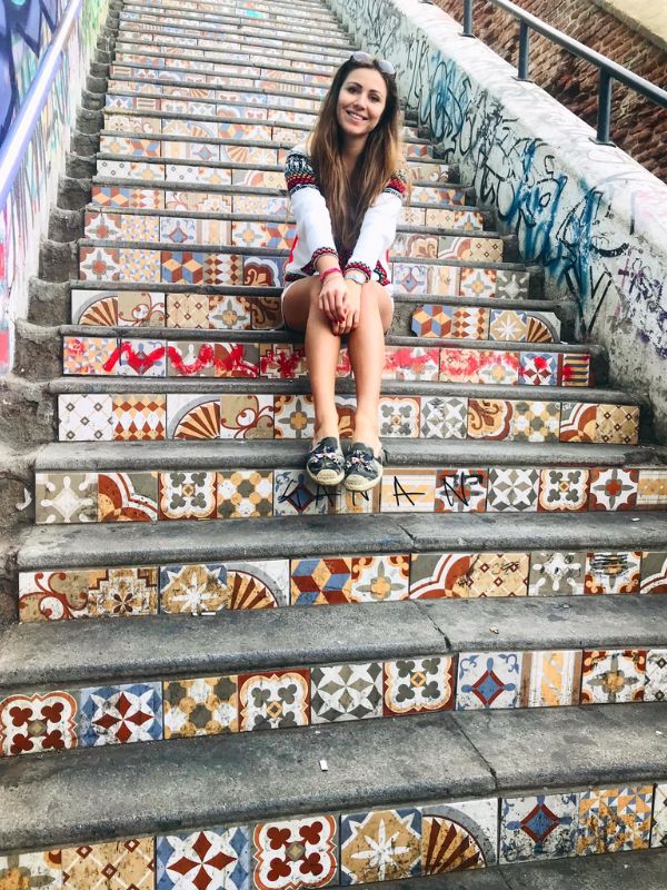 Žena sedí na barevných schodech