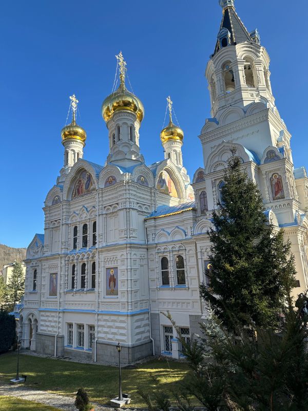 Bílý kostel se zlatými kopulovitými střechami.
