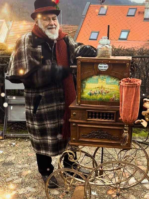 Muž v zimním kabátě a klobouku hraje na flétnu v Lokti.