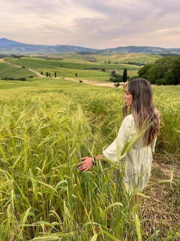 Žena napodobuje scénu z Gladiátora na poli s kopci v pozadí.