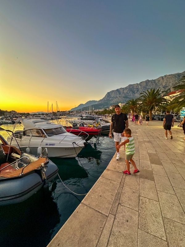 Makarska Chorvatsko Promenáda v Makarské při západu slunce, jachty v přístavu a pohoří Biokovo, Chorvatsko.